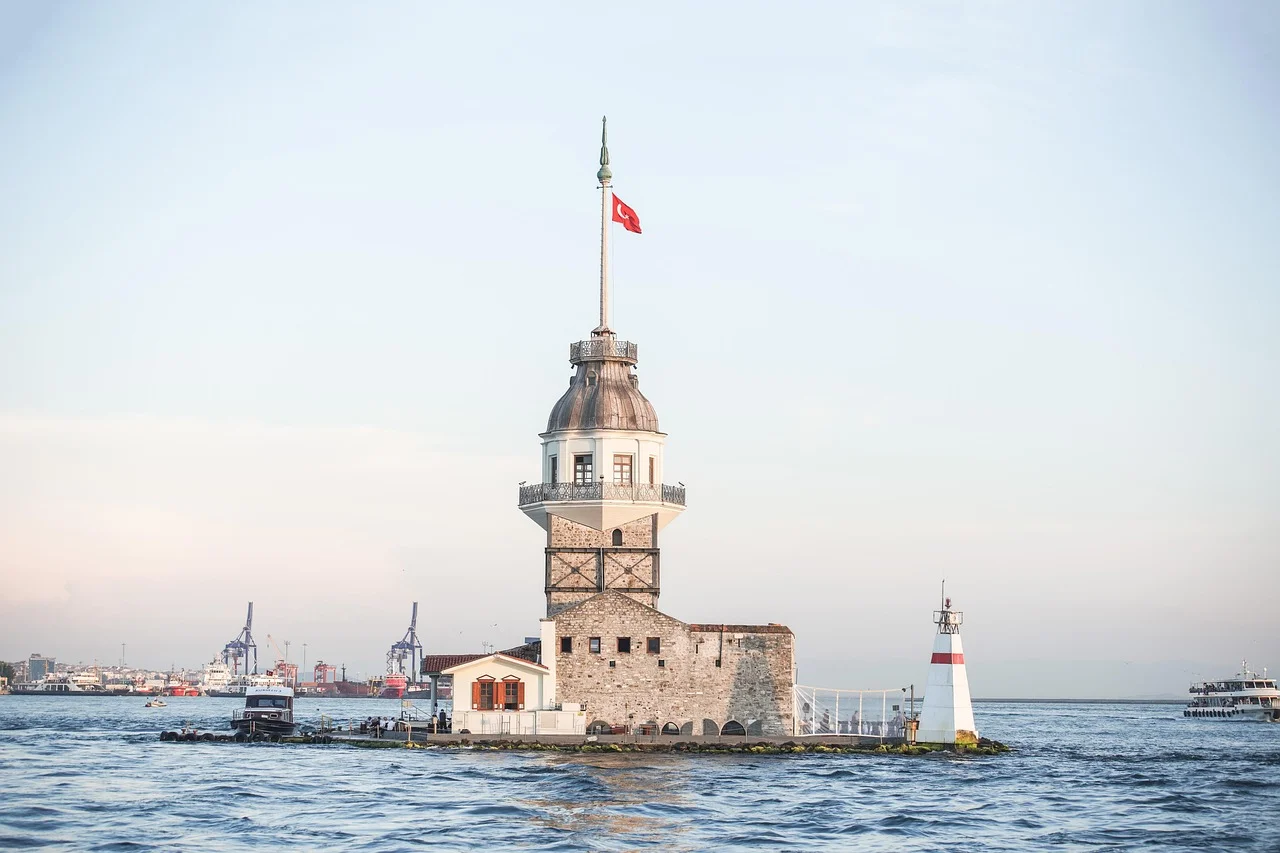 Der Leanderturm (Mädchenturm) im Bosporus, Istanbul, Türkei, bei Sonnenuntergang mit einer Fähre.