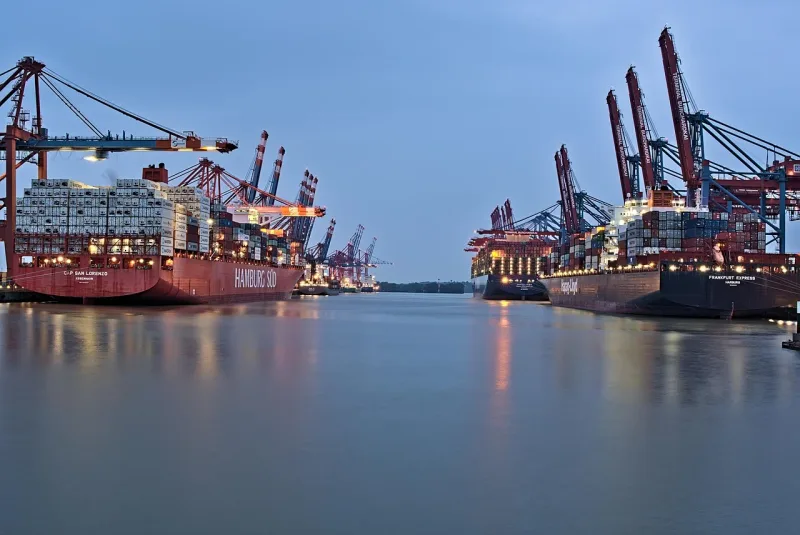 Ein Containerschiff im Hafen mit Kränen bei Sonnenuntergang.