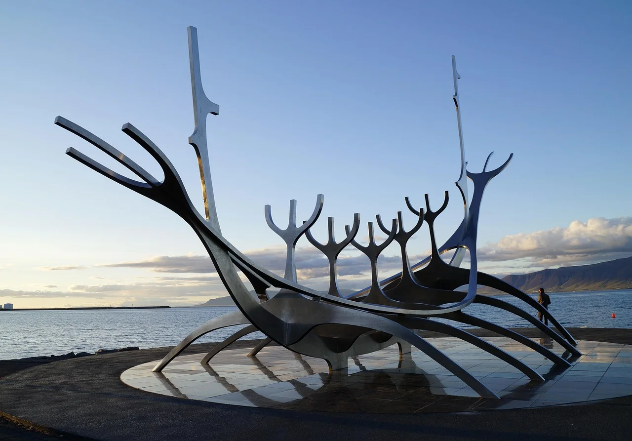 Die Skulptur Sólfar (Sonnenreisender) am Ufer von Reykjavik, Island, mit dem Berg Esja im Hintergrund.