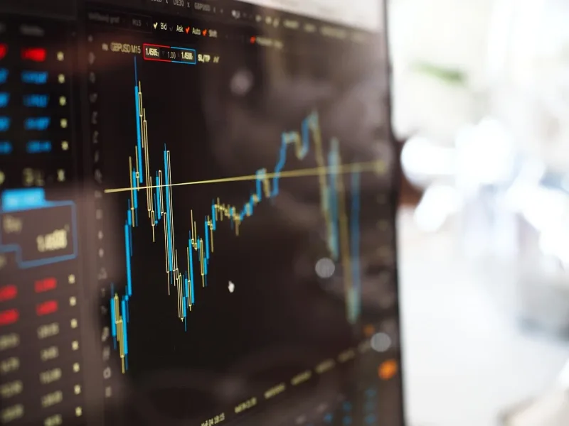 Ein unscharfer Hintergrund zeigt einen Bildschirm mit Finanzdiagrammen, die Wachstum und Marktbewegungen darstellen.