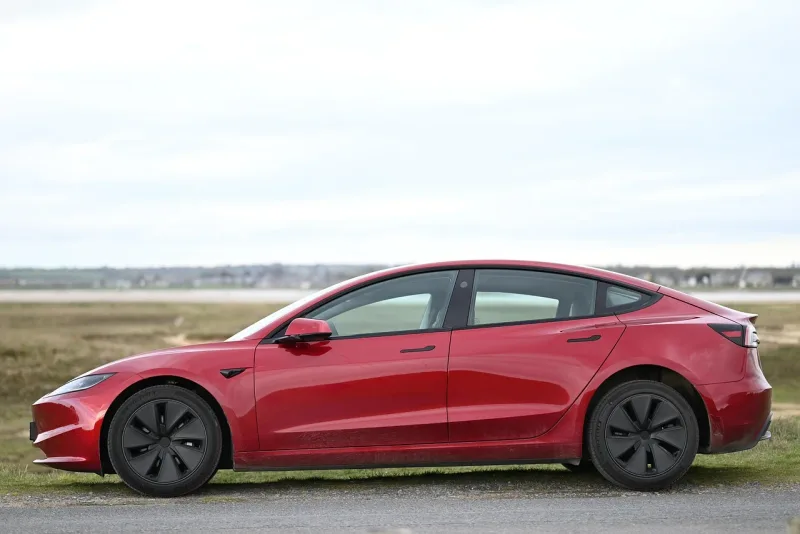 Ein weisser Tesla Model 3 Elektroauto parkiert am Strassenrand.