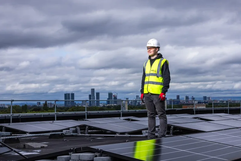 Ein Arbeiter installiert oder wartet Solarpaneele auf einem Hausdach.