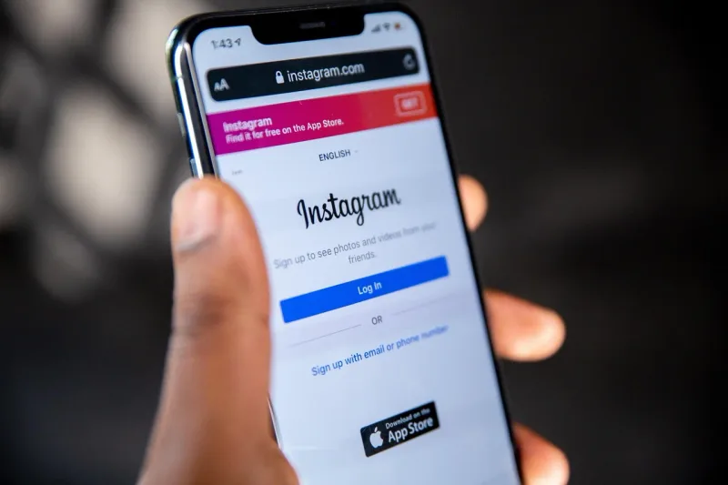 Ein Smartphone-Bildschirm zeigt die Startseite der Instagram-App mit verschiedenen Beiträgen und dem Markenlogo.