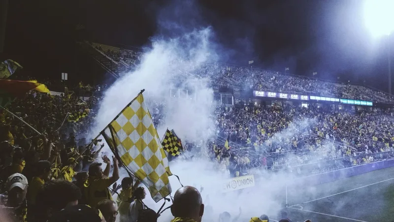 Eine grosse Menschenmenge in einem beleuchteten Fussballstadion während eines Spiels.