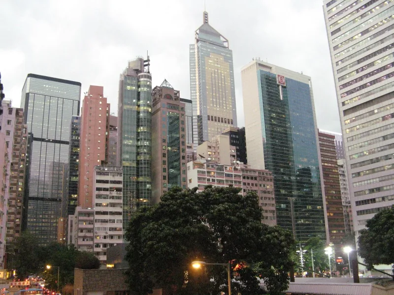 Hohe Wolkenkratzer des Finanzdistrikts von Hongkong bei Dämmerung, die Geschäft und Wirtschaft symbolisieren.