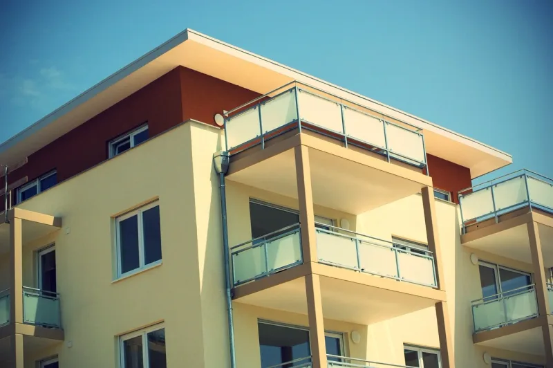 Die Fassade eines Wohngebäudes mit Fenstern und Balkonen in einer städtischen Umgebung.
