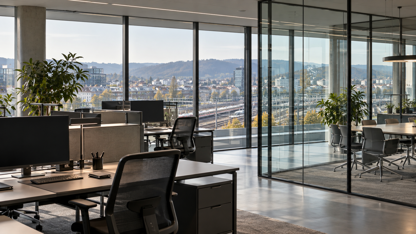 Leere Schreibtische in einem modernen Büro mit Blick auf eine Bahnstrecke.